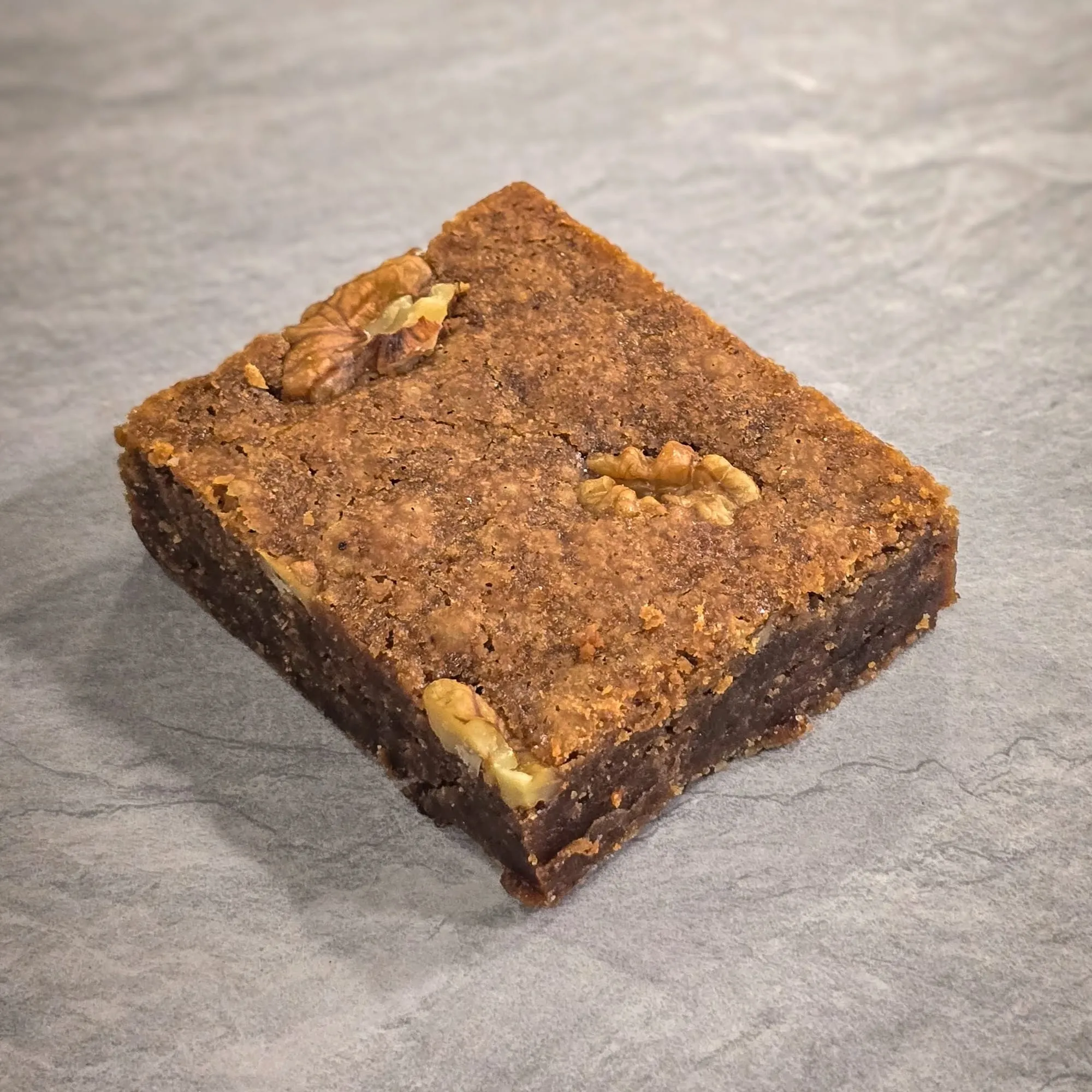 A walnut blondie, cut square, on a stone counter