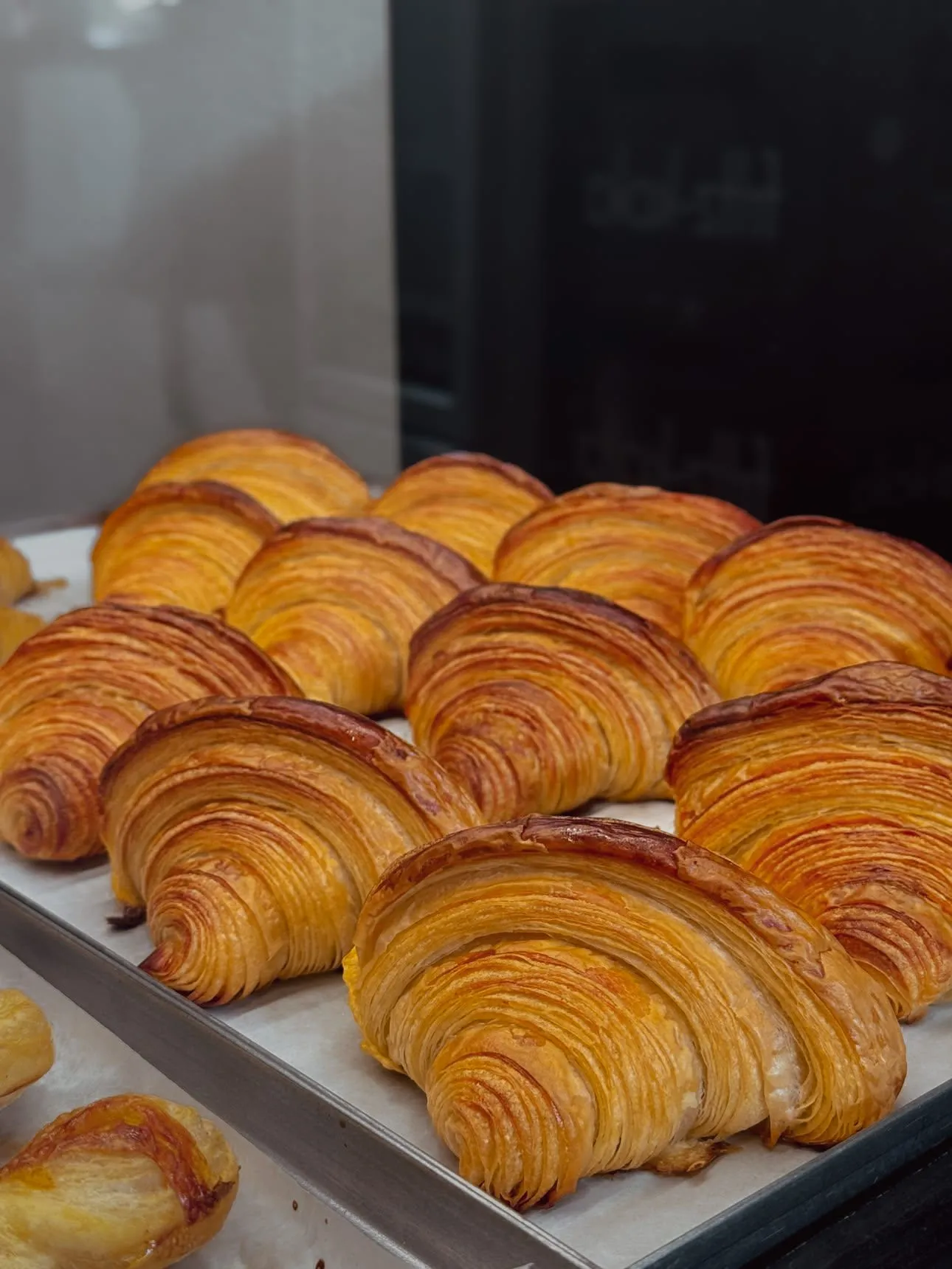 A tray of all-butter croissants, baked to a deep gold with the layers fanned open