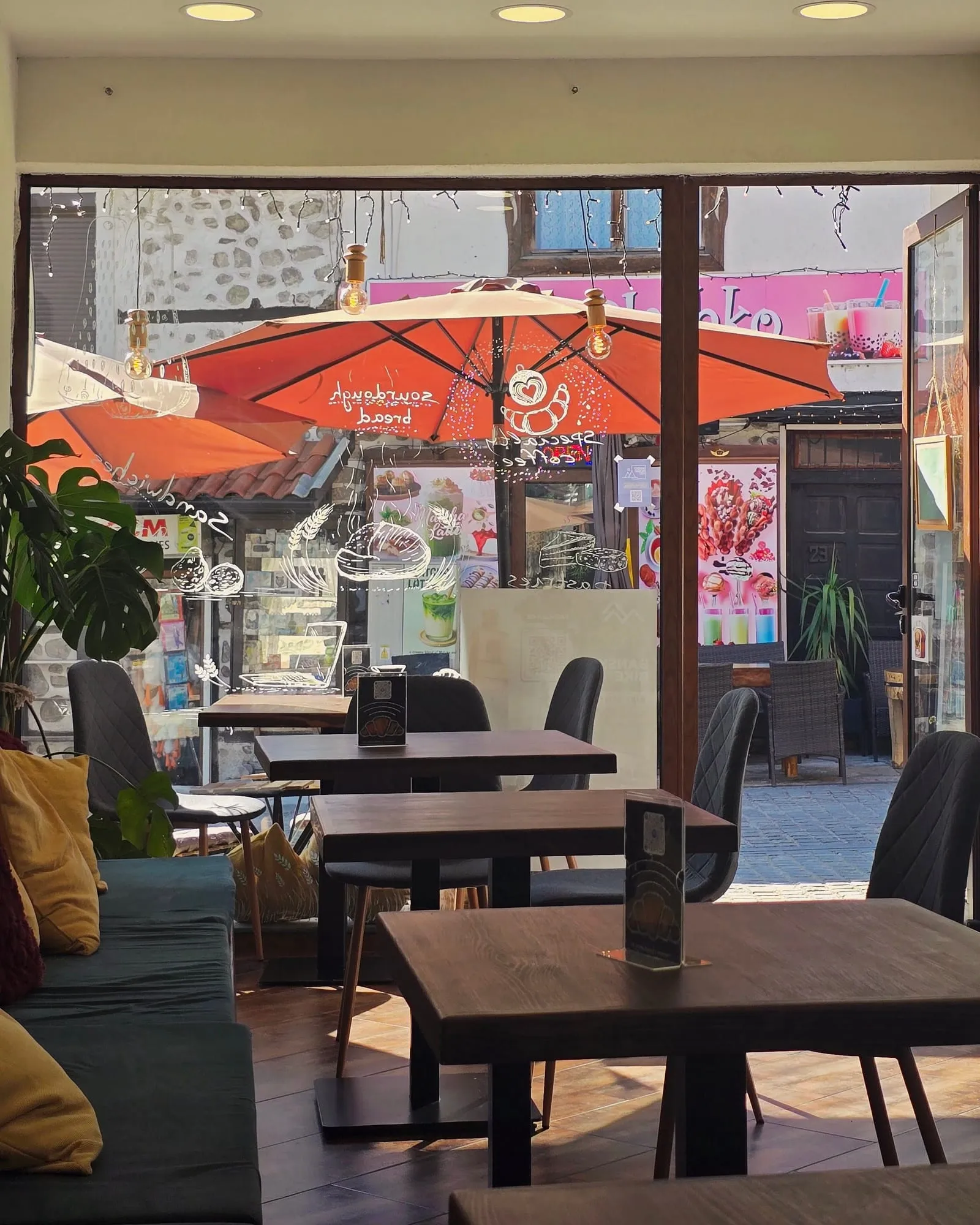 The room at Lembas looking out onto Pirin Street - wooden tables, a cushioned bench under the window and the terracotta parasols outside
